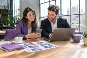 Due professionisti pianificano i contenuti social aziendali su smartphone e laptop
